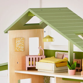 Experience imaginative play with the Tiny Land® Sweetwood Edge Dollhouse - Green & Pink by Tiny Land. This delightful Montessori-inspired wooden dollhouse bedroom features a green roof, a yellow bed, a pink crib, a yellow hanging lamp, wall art, and a potted plant displayed on a warm wooden floor—complete with charming wooden dollhouse furniture to inspire creativity.|Green