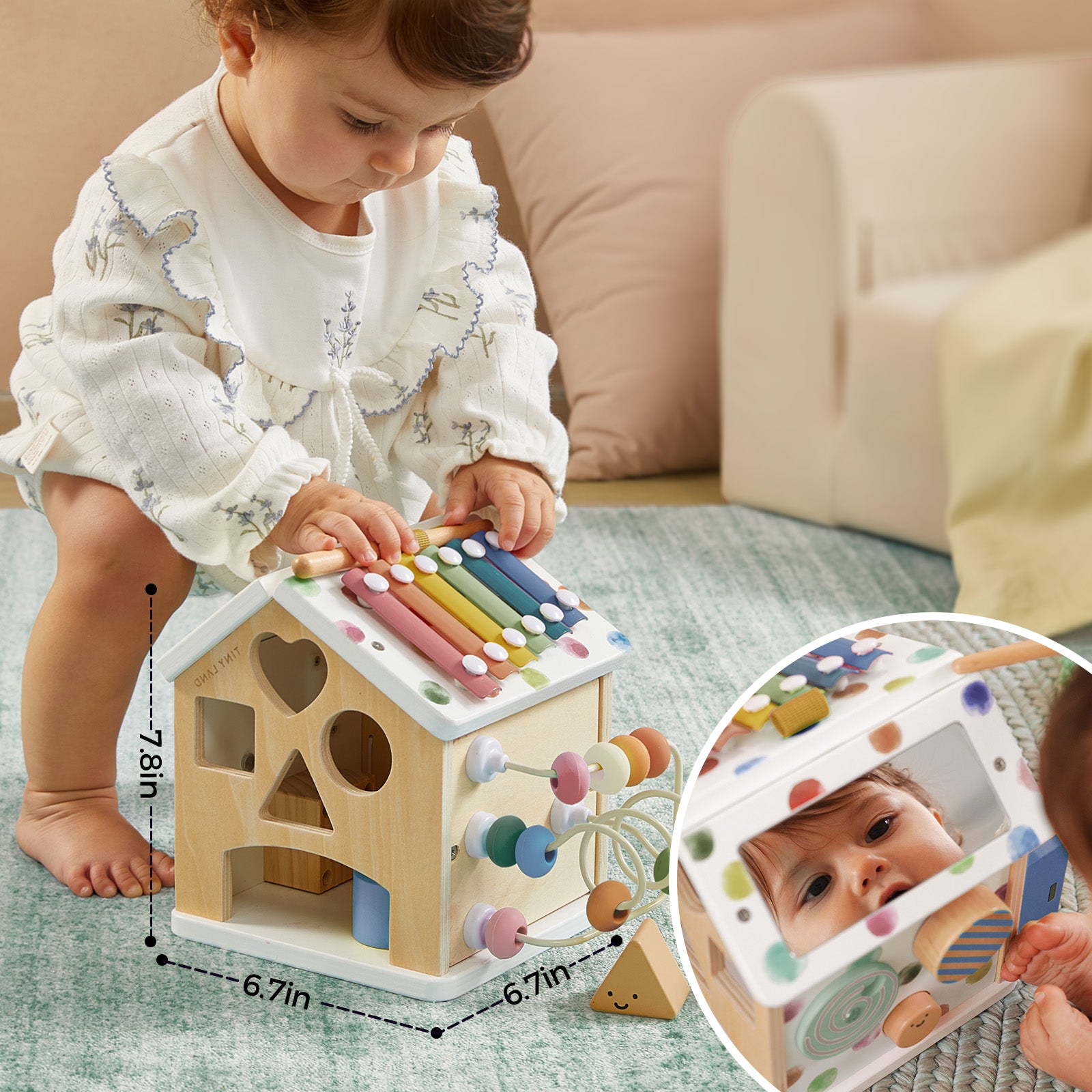 A baby in a white outfit plays with the Tiny Land Cozy Learning Playset—Playmat + Activity Cube, featuring colorful xylophone bars, beads, shape cutouts, and a mirror for self-discovery. An inset displays measurements on this engaging developmental toy.
