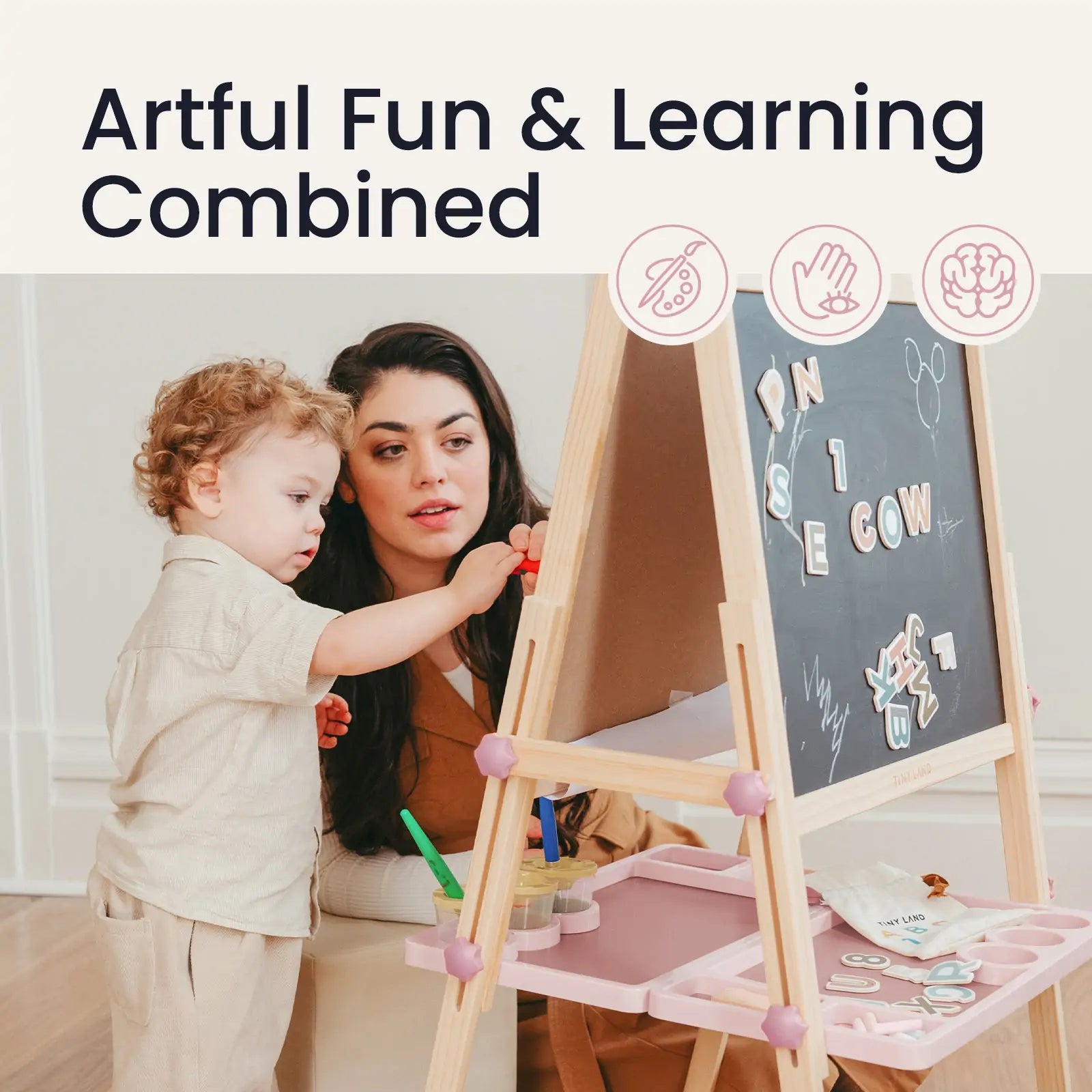 A woman and child play and learn at the Tiny Land® Magnitales Easel for Kids - Pink, a magnetic, height-adjustable easel with art supplies. “Artful Fun & Learning Combined” appears above, with icons showing creativity and cognitive skill development.|pink