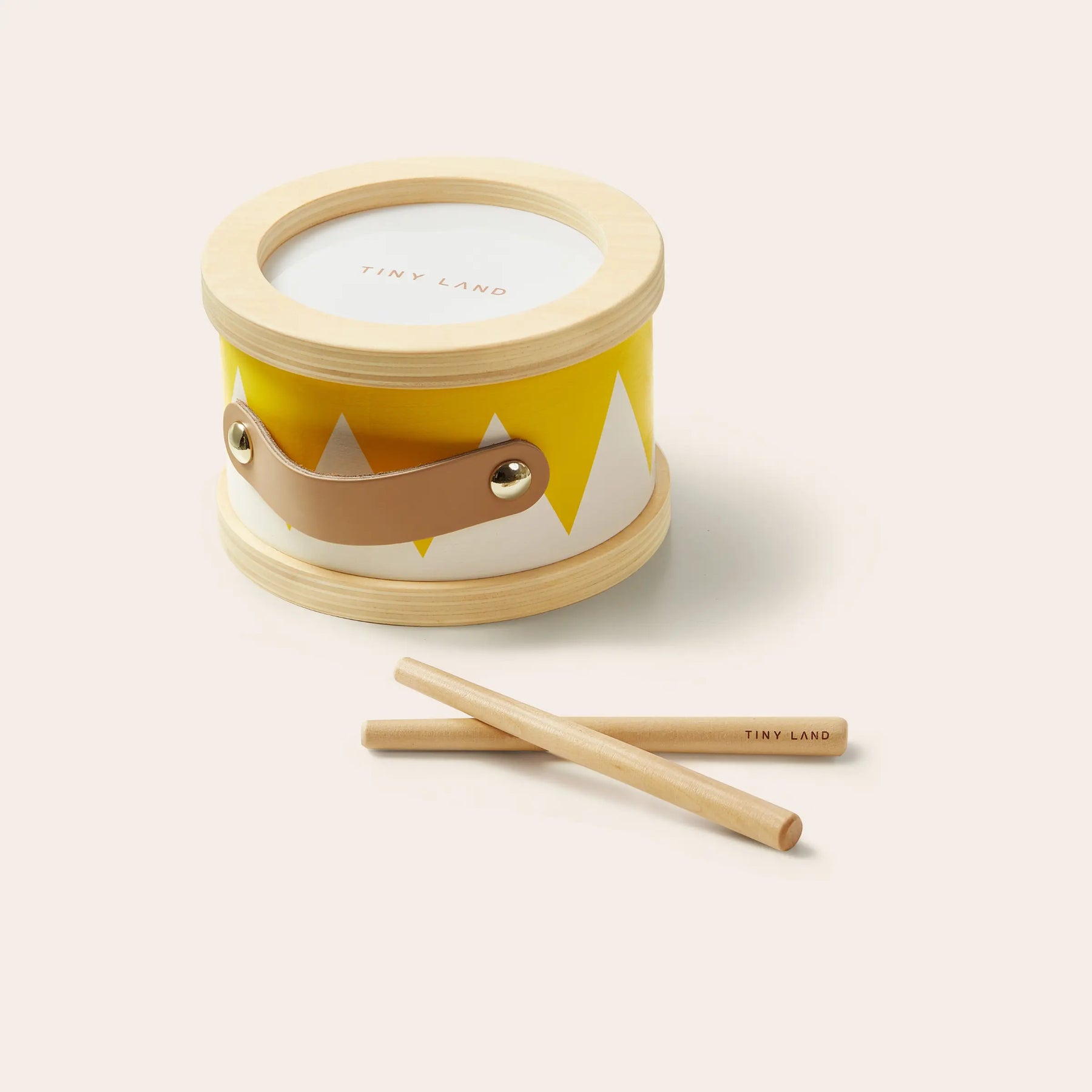 The Tiny Land® Montessori Toys for Toddlers (13–15 Months) features a small wooden drum with a yellow and white zigzag design, brown leather handle, and two wooden drumsticks—perfect for early learning and sensory play.
