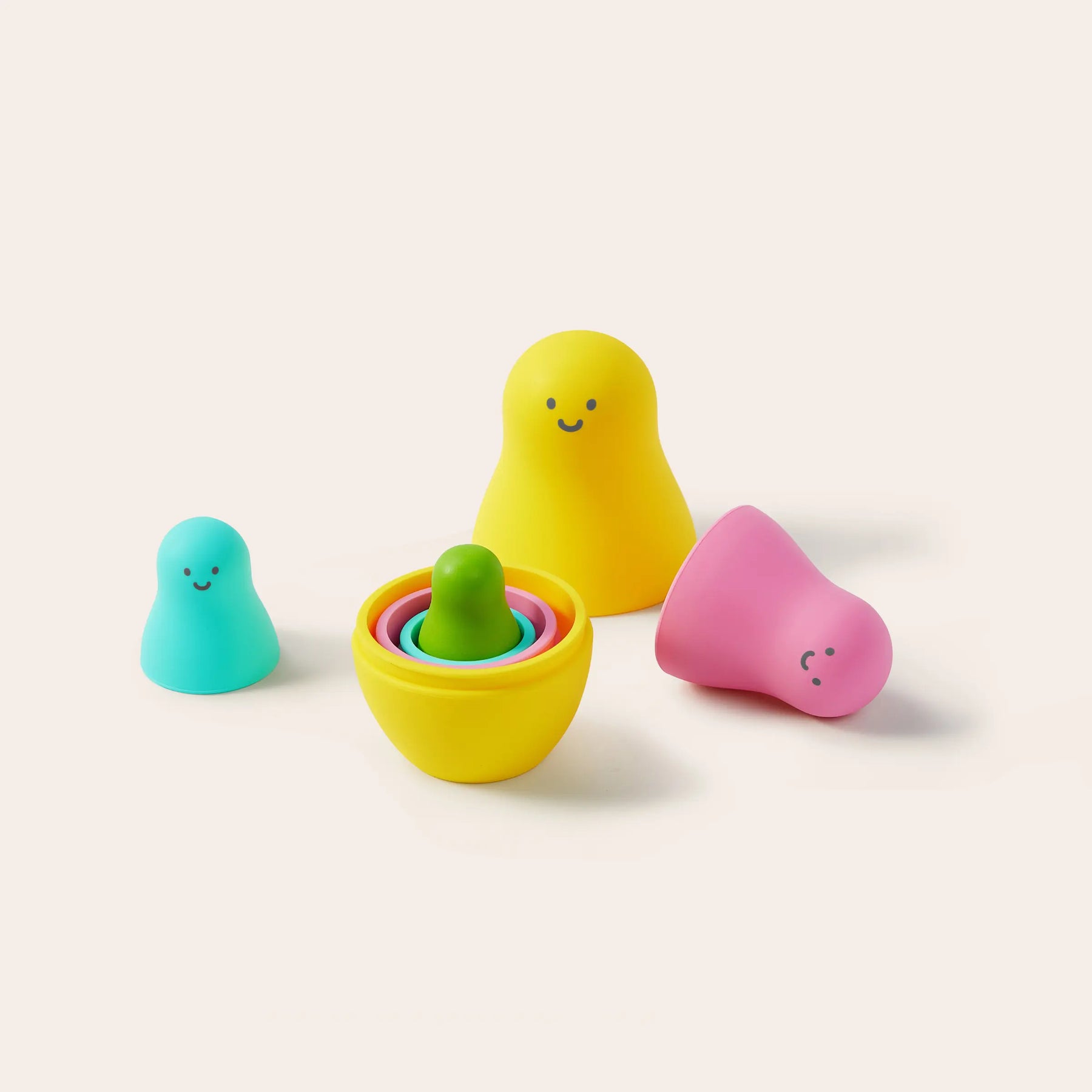 Four colorful Tiny Land® Montessori Toys for Toddlers (16–18 Months) feature smiling blobs on a light background. The open yellow toy reveals smaller rings inside, with teal, pink, and another small piece nested within it.