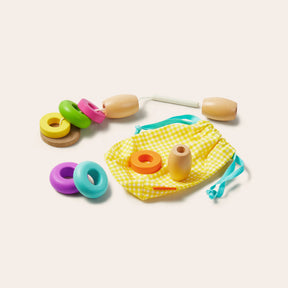 Tiny Land® Montessori Toys for Toddlers (16–18 Months) is a colorful wooden lacing set with donut-shaped rings, 2 handles, a white string, and a yellow pouch—an ideal Montessori educational toy by Tiny Land.