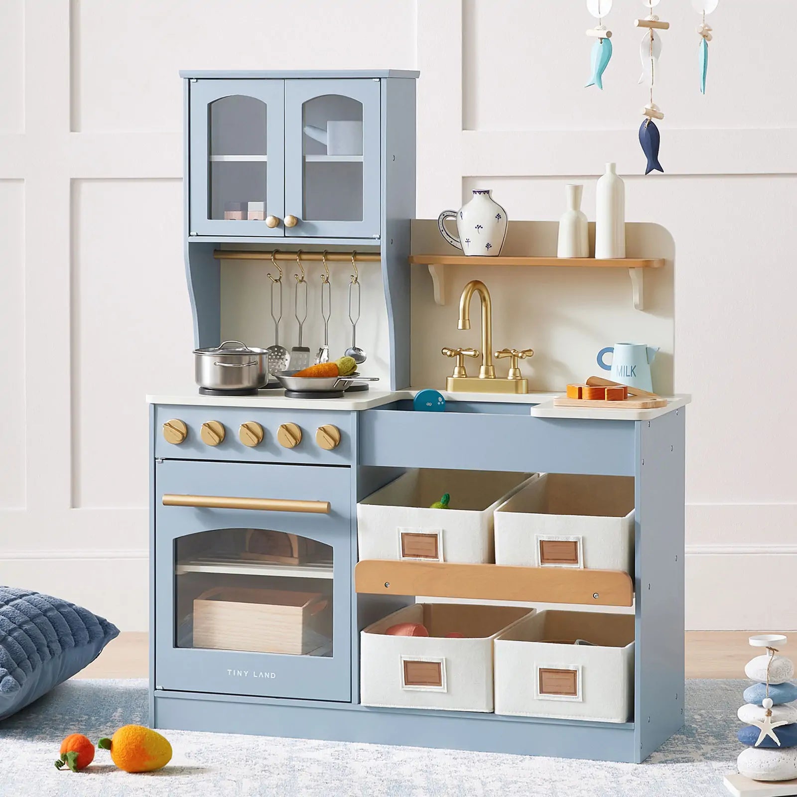 The Tiny Land® Serenity Wooden Play Kitchen for Kids in blue & green includes a stove, oven, sink, pots, utensils, toy kettle, shelves, and four fabric bins—ideal for imaginative play. Soft toys and décor can be placed nearby.|blue