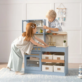 Two children enjoy imaginative play with the Tiny Land® Pretend Play Kitchen for Kids - Serenity Wooden Kitchen in Blue & Green. The girl opens the oven while the boy reaches for pretend cookware, both fully engaged in creative fun.