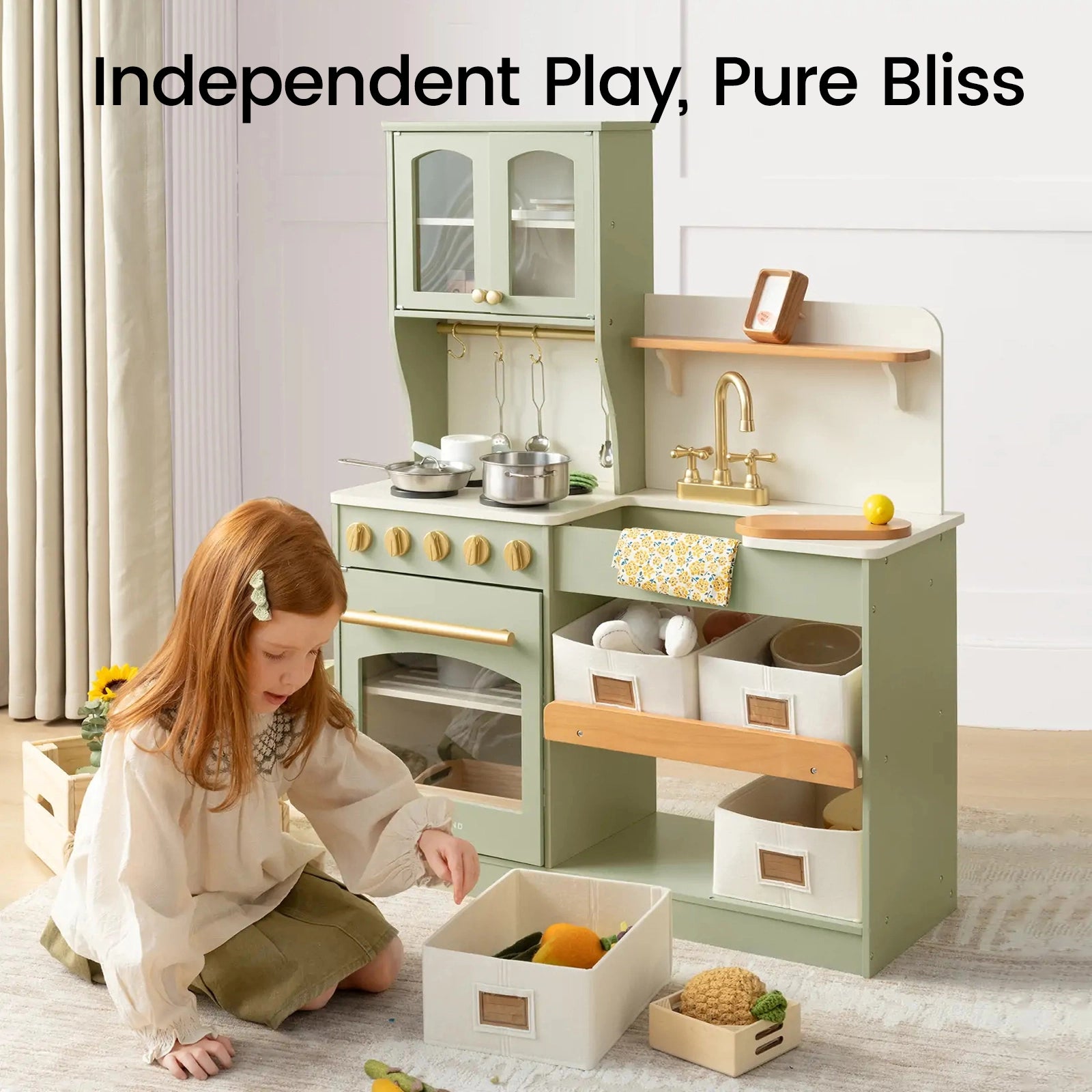 A young girl enjoys imaginative play with the Tiny Land® Wooden Play Kitchen with Storage for Creative Toddlers by Tiny Land, complete with a stove, sink, and shelving bins for effortless organization. This storage play kitchen inspires hours of creative fun with pretend cookware. Text above reads: Independent Play, Pure Bliss.|sage