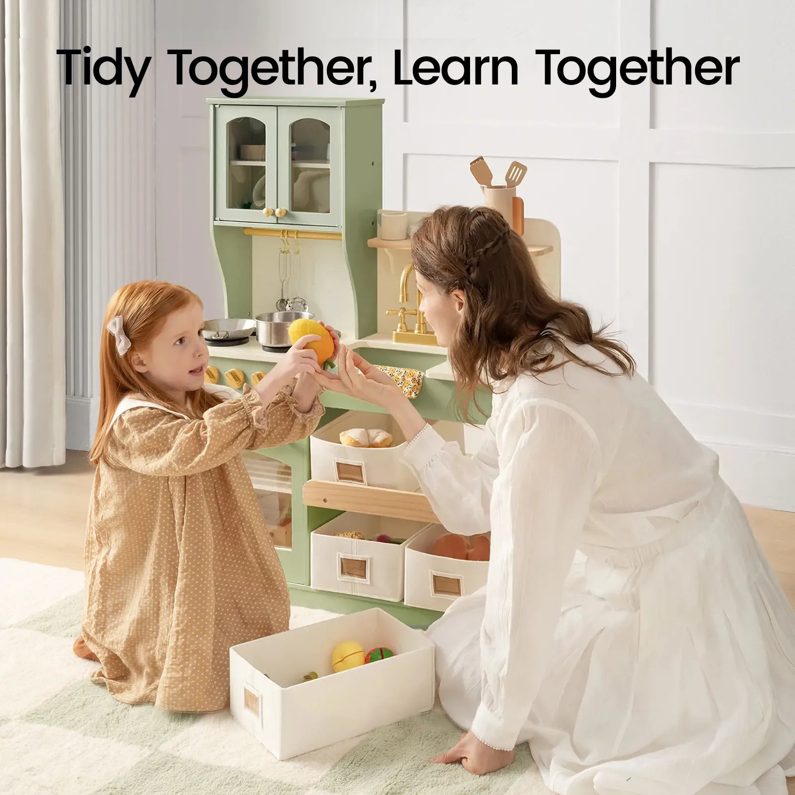 A woman and a young girl tidy up toy food and pretend cookware in the Tiny Land® Wooden Play Kitchen with Storage for Creative Toddlers by Tiny Land. The text above them reads, Tidy Together, Learn Together.|sage