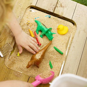 A child’s hand explores sensory play with toy dinosaurs, a yellow duck, colorful worms, and a pink scoop—perfect to use with the Tiny Land® Mud Kitchen - DuoPlay Outdoor Play Kitchen for Kids by Tiny Land.