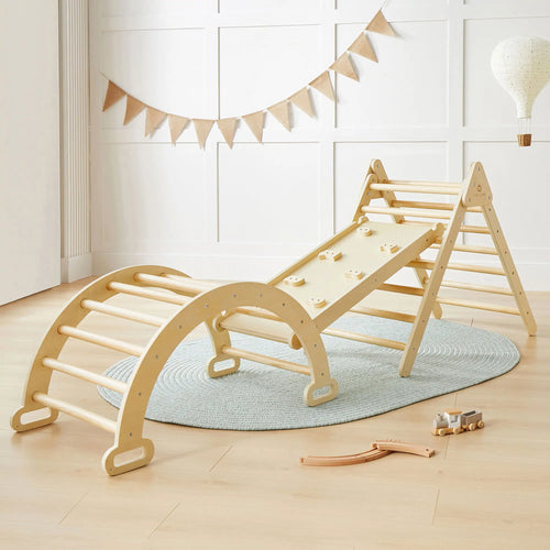 The Tiny Land Safe Explorers Playset, featuring a natural wood arch, ramp, and climber on the Urban Zoo playmat, sits alongside a toy train and tracks. Bunting and a hot air balloon decoration adorn the background.|natural wood color