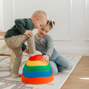 A boy balances on a Tiny Land® Stepping Stones - Rainbow Color while a girl steadies it beside him. They play together on a mat, building motor skills and teamwork with this fun Tiny Land toy in a bright room.|Rainbow Color
