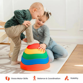 A toddler steps on colorful stacking rings, much like an obstacle course, while an older child supports him. The scene suggests play that builds gross motor skills, balance, and stability—just like with Tiny Land® Stepping Stones - Rainbow Color from Tiny Land. Icons below indicate these benefits.