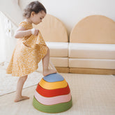 A young child in a yellow dress steps onto Tiny Land® Stepping Stones - Vintage Color, building motor skills in a bright playroom with a beige couch and soft mat.|Vintage Color