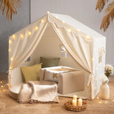 The Tiny Land® Kids Tent – Large Cozy Tent with Star Lights by Tiny Land features soft pillows, a blanket, and a small sofa on a woven rug, creating a warm, inviting atmosphere perfect for kids to play and relax.|fabric