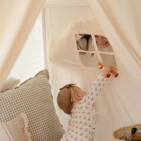 A baby reaches through the Tiny Land® Kids Tent – Large Cozy Tent with Star Lights to hand a toy to a smiling adult, with cozy pillows and a quilted play mat from Tiny Land visible inside.|fabric