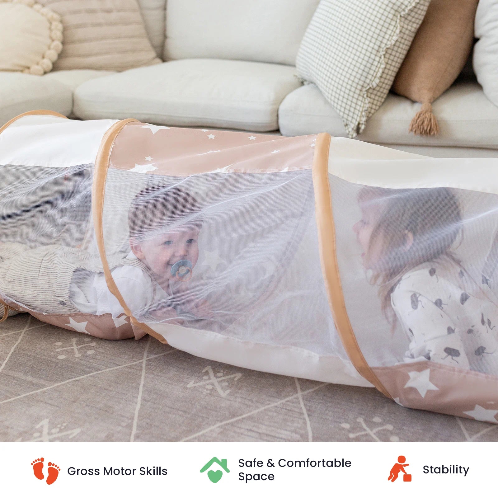 Two small children crawl through the Tiny Land® Adventure Play Tunnel by Tiny Land on a carpeted floor, with pillows and a couch in the background. This versatile play tunnel is perfect for both indoor and outdoor fun. Icons below highlight its support for gross motor skills, safety, and stability.|brown
