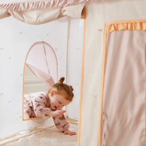 A young child smiles and reaches out from a Tiny Land® Sweet Citrus Kids Play Tent by Tiny Land, a cozy white and pink indoor playhouse perfect for fun adventures on its soft padded floor.|pink