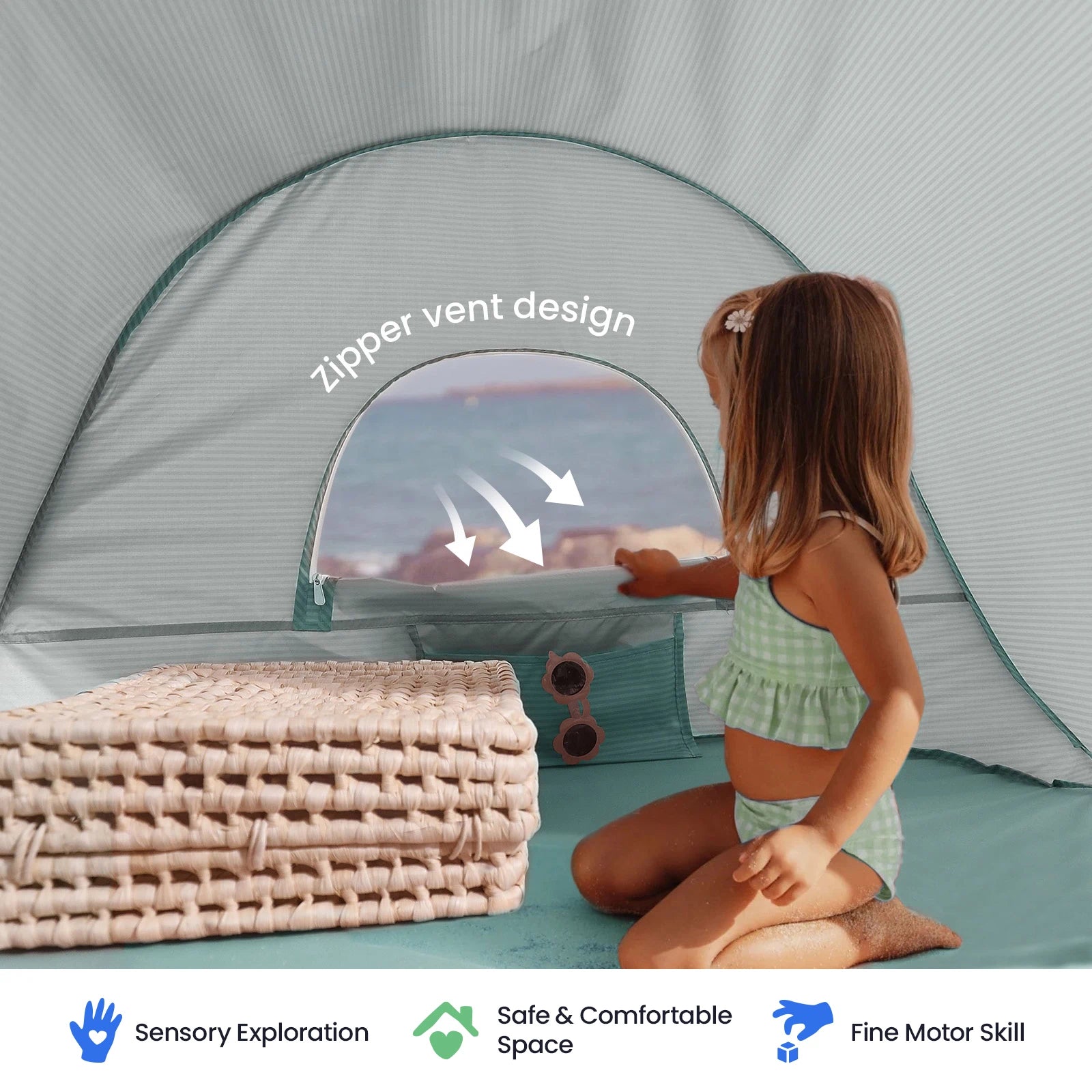 A young girl in a green swimsuit sits inside the Tiny Land® Baby Beach Tent – Play Tent for Outdoor Fun by Tiny Land, featuring a zippered vent, with folded mats and sunglasses beside her. Icons below highlight sensory exploration, a safe play space, and fine motor skill benefits.|Sea Blue