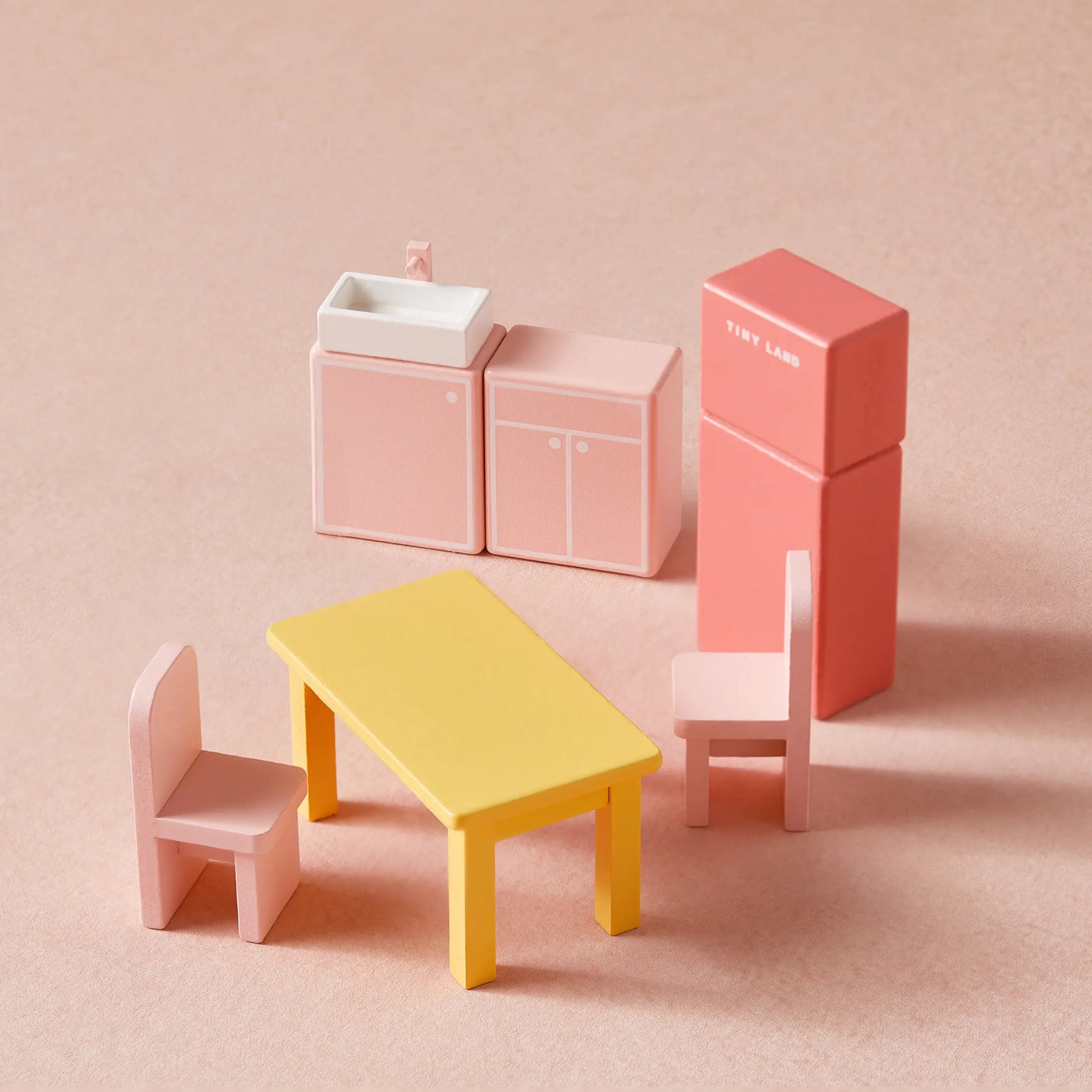 The Tiny Land Sweet Dreams Playset features a pink dollhouse and pink-white playhouse, complete with a yellow table, two pink chairs, sink, cabinet, and refrigerator—perfect for any girl's dollhouse collection.|pink