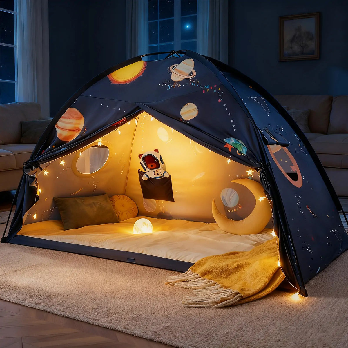 The Tiny Land® Kids Bed Tent by Tiny Land features planets, stars, and warm string lights. Inside, cushions, a yellow throw, a round moon pillow, and a night light create a dreamy hideaway for kids in the living room.|SPACENEST