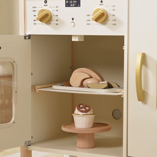 The Tiny Land® PopJoy Kitchen & Fridge Set features an open toy oven displaying wooden play food—a cupcake with a pretzel on the bottom shelf and a roast with veggies on the middle tray—perfect for pretend play.