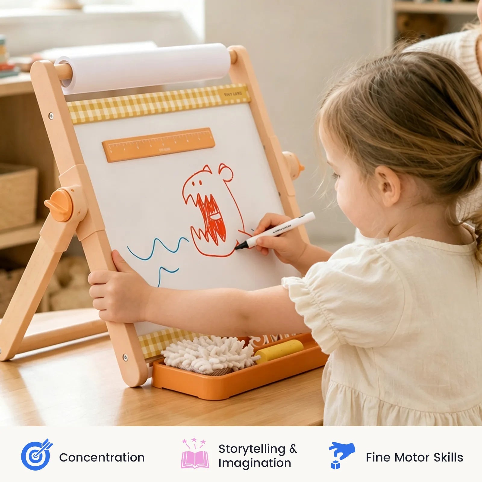 A young child draws a red monster and blue waves on the Tiny Land® Double-Sided Magnetic Tabletop Easel. The scene emphasizes skills like concentration, storytelling, and fine motor development, illustrated with icons and labels at the bottom.|Oatmeal
