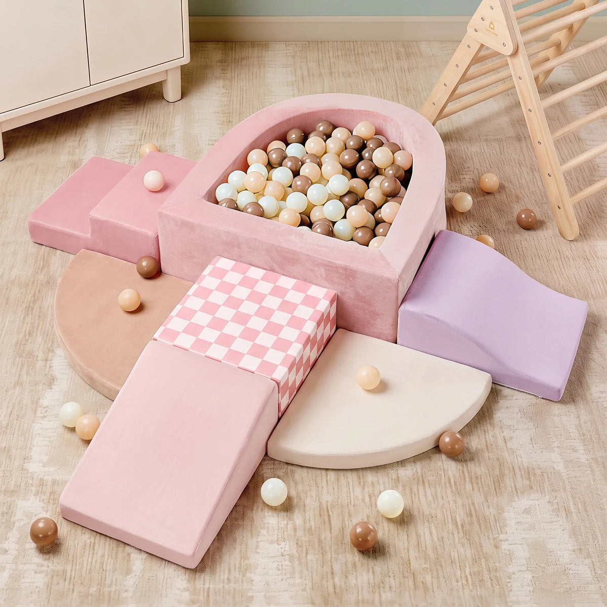 The Tiny Land® Violet PlayNest Climbing & Ball Pit Set by Tiny Land features soft pastel climbing blocks, foam ramps, steps, and a cozy ball pit filled with beige, white, and brown balls—all arranged on a wooden floor next to a wooden climbing structure—making it perfect for sensory play.|Pink