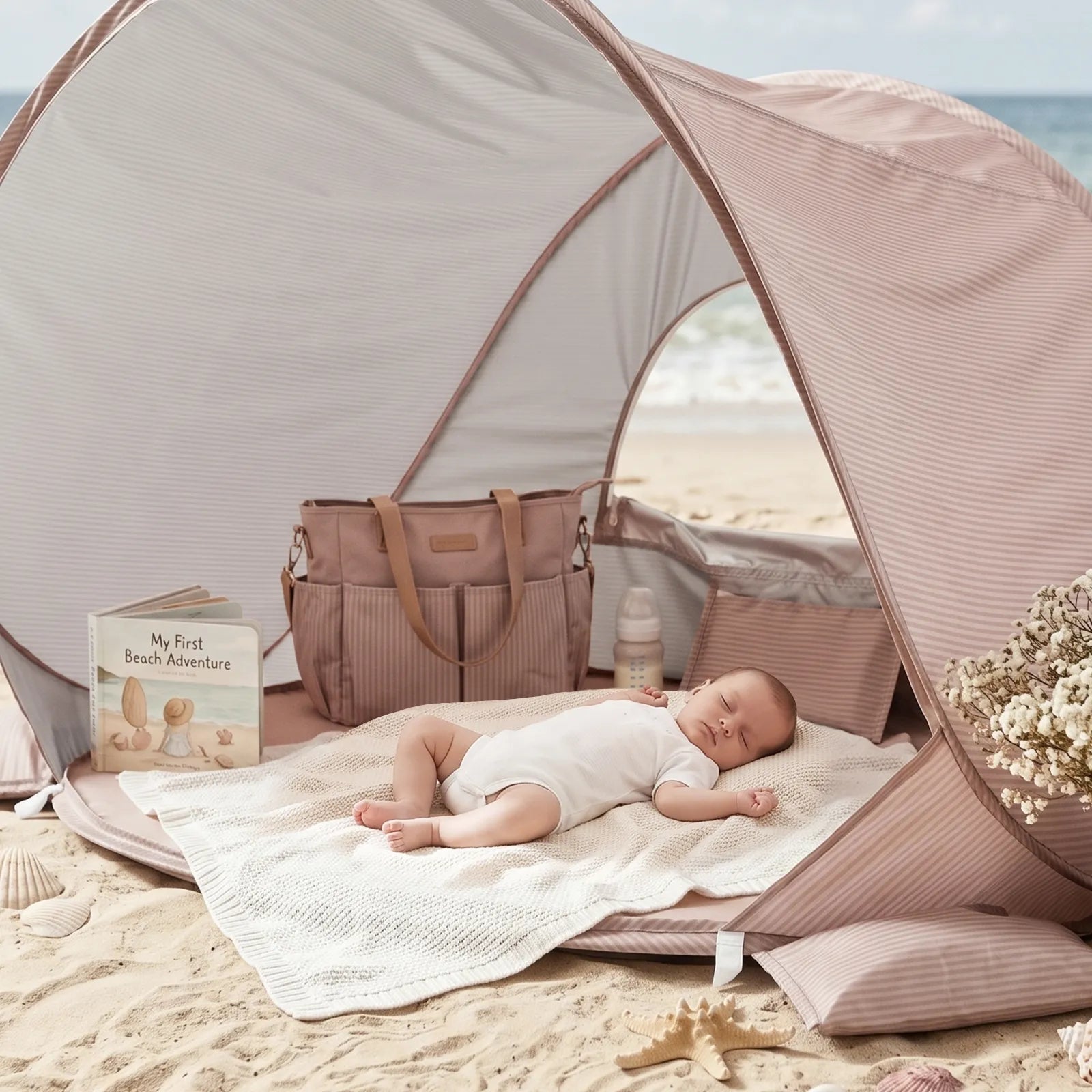 A baby sleeps peacefully in a Tiny Land® Baby Beach Tent & Sand Toy Set with pink stripes, nestled on the sand by the ocean. Nearby are a Tiny Land tote bag, a baby bottle, the book "My First Beach Adventure," and some flowers, creating a calm and cozy scene.|Pink