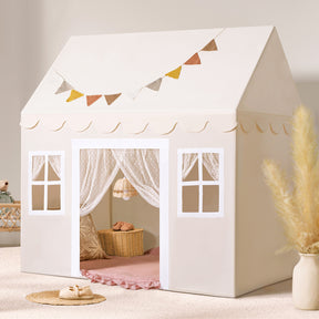 The Tiny Land® Playhouse Tent – Natural Cream Indoor Tent for Kids by Tiny Land features scalloped trim, window designs, lace curtains, and a fabric bunting, set on a soft rug with pampas grass and a basket in a cozy, sunlit room|white