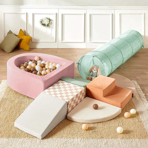 The Tiny Land® PlayNest Climbing Ball Pit Set with Tunnel by Tiny Land features pastel climbing blocks, a pink foam ball pit, mint green tunnel, steps and ramps on a beige rug—ideal for creating a fun indoor play area for kids.